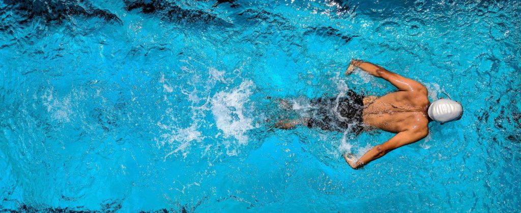 An aerial view of a competitive swimmer executing the butterfly stroke in a pool. 