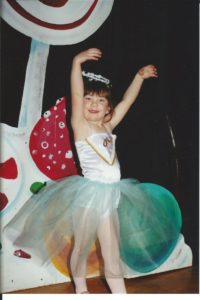 A young girl shows off her tutu at a dance recital.